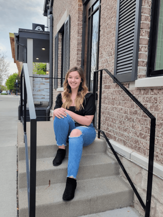 Young Woman Sitting On Steps Outside Brick Building | Air Control Products Mercedes Shultz awarded Geis Scholoarship
